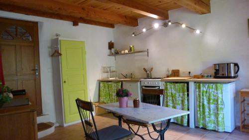 Il comprend une cuisine avec une table et des portes vertes. dans l'établissement Gite nature les ANOURES en PROVENCE, à Mollans-sur-Ouvèze
