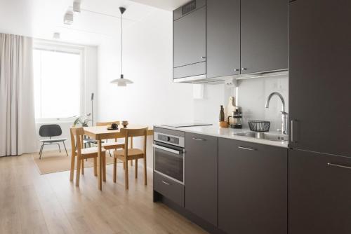 a kitchen with gray cabinets and a wooden table at Noli Otaniemi in Espoo