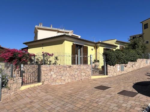 a yellow house with a fence and a brick driveway at Villa Sole e Luna - Key to Villas in Valledoria