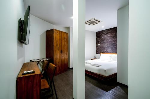 a bedroom with a bed and a desk and a tv at Elite Hotel Asok Sukhumvit 20 in Bangkok