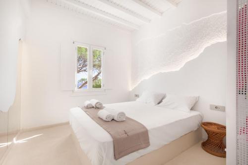 a white bedroom with a bed with towels on it at Sunset Cove in Agios Ioannis Mykonos
