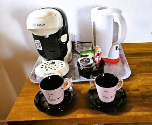 a table with two coffee cups and a coffeemaker at La GRANGE D'AZE in Azé