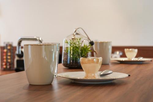 a wooden table with two cups and a plate and spoon at Maison centre Bourgueil avec piscine 8 p in Bourgueil