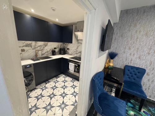a small kitchen with black cabinets and a blue chair at Gloucester - Apartment - Sleeps 2 - Parking - 97WS in Gloucester