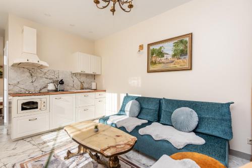 a living room with a blue couch and a table at Ąžuolo vila in Karklė