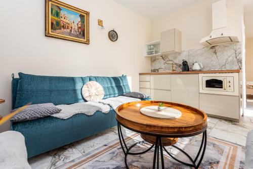 a living room with a blue couch and a table at Ąžuolo vila in Karklė