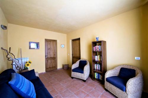 a living room with two chairs and a book shelf at Fienile di Colletalli by VacaVilla in Radicondoli