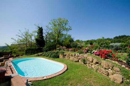 a swimming pool in a garden with flowers at Fienile di Colletalli by VacaVilla in Radicondoli