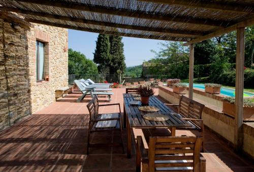 a patio with a table and chairs and a pool at Fienile di Colletalli by VacaVilla in Radicondoli