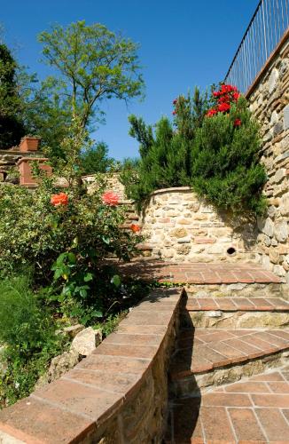 a stone retaining wall with a stone staircase with flowers at Fienile di Colletalli by VacaVilla in Radicondoli