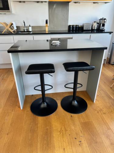 a kitchen with two stools under a counter at Twickenham Fraser Apartments in Twickenham