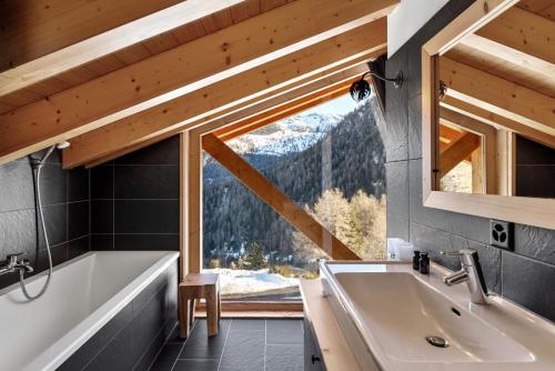 a bathroom with a tub and a sink and a window at Chalet 18 îles Luxury chalet With Sauna La Tzoumaz in Riddes