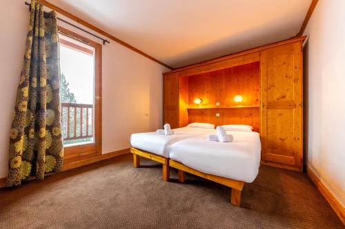 two beds in a room with a window at Résidence Les Arolles by Les Etincelles in Arc 2000