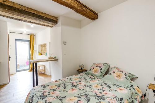 a bedroom with a bed with a floral bedspread at Charmant studio à 5 minutes de villefranche in Lacenas