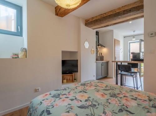 a bedroom with a bed with a floral bedspread at Charmant studio à 5 minutes de villefranche in Lacenas