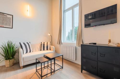 un salon avec un canapé et une télévision sur un mur dans l'établissement Studio équipé pour une personne, à Villeneuve d'Ascq