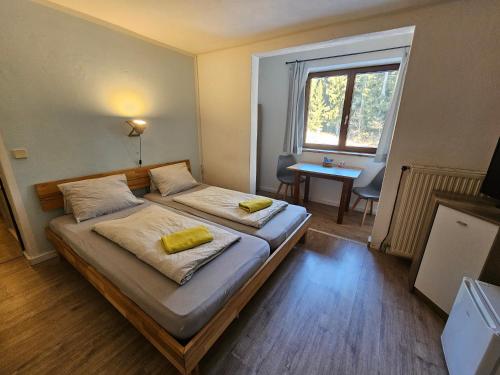 a bedroom with two beds and a window and a desk at Karawanken Lodge in Faak am See