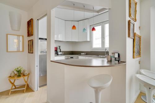 une cuisine avec des armoires blanches et un comptoir dans l'établissement Bastille Apt design with AC terrace 5 people by Weekome, à Paris