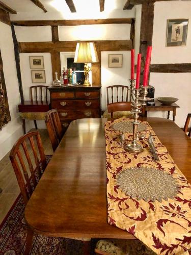 a dining room with a wooden table with red candles on it at Logaston Common Farmhouse in Woonton