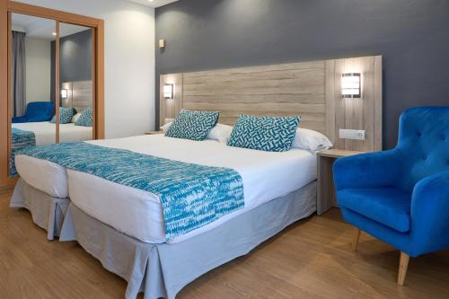 a bedroom with a large bed and a blue chair at Hotel Maya Alicante in Alicante