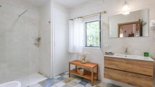 ein weißes Badezimmer mit Waschbecken und Spiegel in der Unterkunft Huerta Valleciruelo Sanlúcar La Mayor by Ruralidays in Sanlúcar la Mayor
