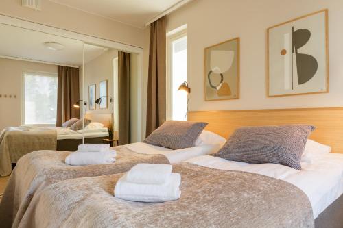 two beds in a hotel room with towels on them at Marina Chalets 1 bedroom apartments by Hiekka Booking - sisältää liinavaatteet ja loppusiivouksen in Kalajoki