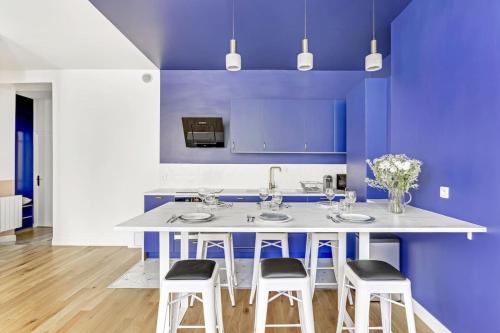 une cuisine avec des murs violets et un îlot blanc avec des tabourets dans l'établissement Blue Design 2BDR Flat in the Heart of Bastille, à Paris
