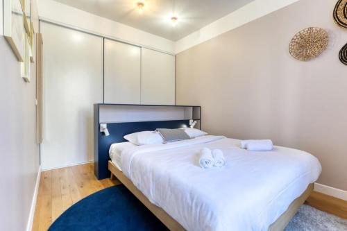 une chambre avec un grand lit blanc avec des serviettes dessus dans l'établissement Blue Design 2BDR Flat in the Heart of Bastille, à Paris