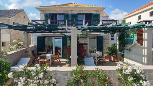 a house with a patio with chairs and an umbrella at Apartment Ennio in Povlja