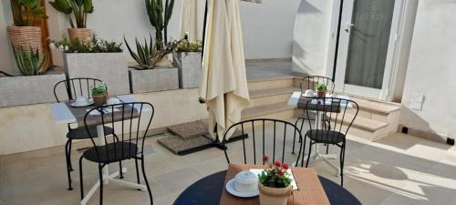 a patio with two tables and chairs and an umbrella at Le Dune Luxury Rooms in Vieste