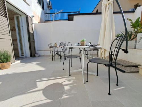 a patio with a table and chairs and an umbrella at Le Dune Luxury Rooms in Vieste