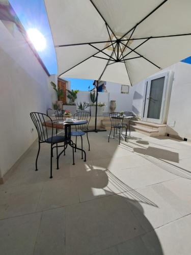 a patio with tables and chairs and an umbrella at Le Dune Luxury Rooms in Vieste