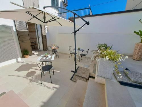 a patio with a table and chairs and an umbrella at Le Dune Luxury Rooms in Vieste