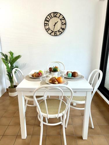 une table blanche avec des chaises et une horloge sur le mur dans l'établissement Mon rêve mer, à Les Sables-dʼOlonne