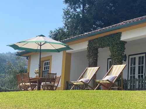 a table and chairs with an umbrella in front of a house at Casa de Santiago in São Tiago de Besteiros