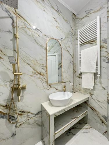 a marble bathroom with a sink and a mirror at COLLINE Rezidențial in Rediu