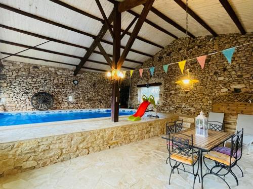 a room with a table and chairs and a stone wall at Refuge Champêtre - Piscine intérieure - Détente in Salles