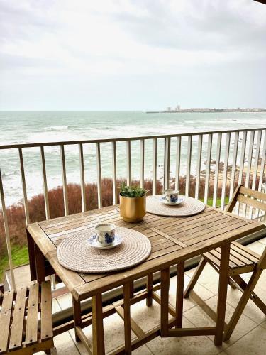 - une table en bois sur un balcon avec vue sur la plage dans l'établissement Horizon bleu, à Les Sables-dʼOlonne