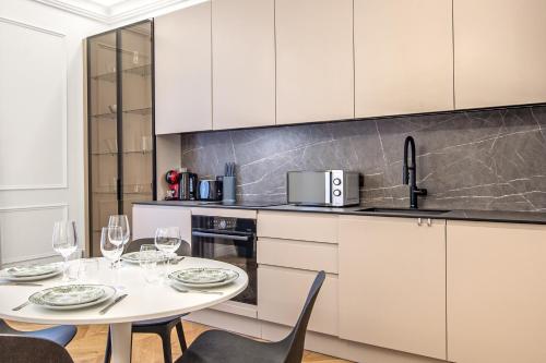 une cuisine avec des armoires blanches et une table et des chaises dans l'établissement 2mn Monaco - Rénovation Luxe - CU, à Beausoleil