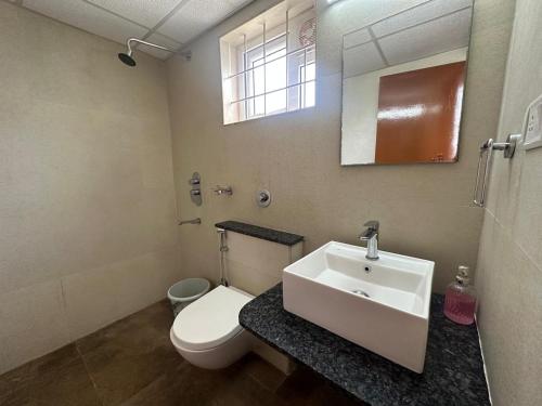 een badkamer met een wit toilet en een wastafel bij Achates Corporate Services in Bangalore