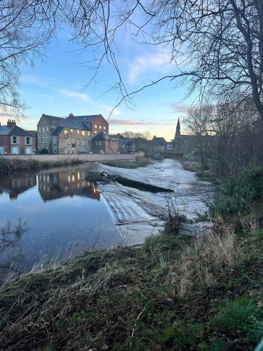 a river in a small town with houses and a town at Town Centre Apartments with Spa in Morpeth
