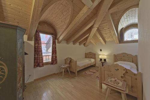 a bedroom with a bed and a room with wooden ceilings at Chesa Mastrel - Silvaplana in Silvaplana