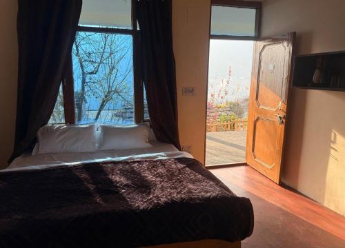 a bedroom with a bed and a large window at hotel in manali by Aura in Vashisht