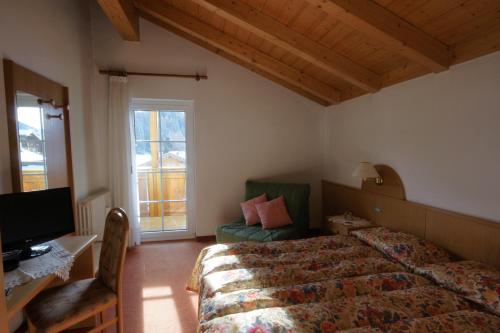 a bedroom with a bed and a desk and a television at Hotel Villa Cima Undici in Pozza di Fassa