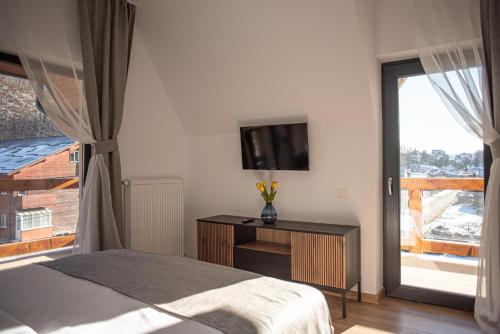 a bedroom with a bed and a tv and a window at Yael Luxury Apartments 5 in Buşteni