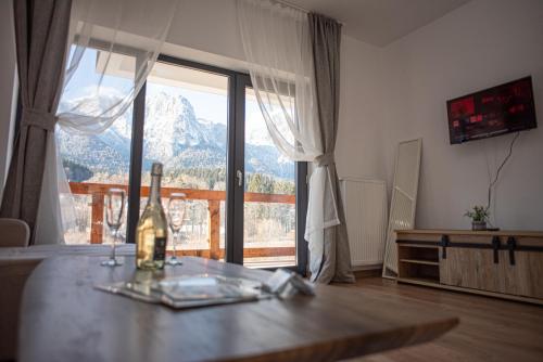 a room with a table with a bottle of wine and a window at Yael Luxury Apartments 5 in Buşteni