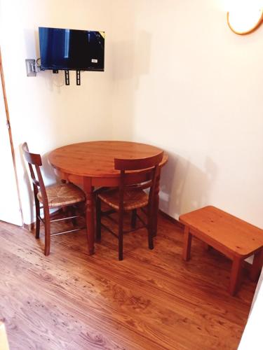une table en bois avec deux chaises et une télévision. dans l'établissement Terrasses D 103 - PARC NAT VANOISE studio 2 pers, à Val Cenis