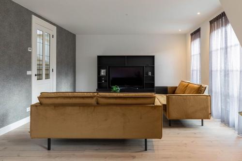 a living room with a couch and a flat screen tv at Luxe 3-kamer Penthouse met dakterras in het centrum van Hoorn in Hoorn