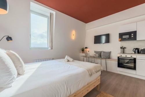 une chambre avec un grand lit blanc et une fenêtre dans l'établissement Studio équipé côté cour, parking gratuit, à Villeneuve d'Ascq
