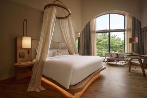 ein Schlafzimmer mit einem Himmelbett in der Unterkunft dusitD2 Khao Yai in Mu Si